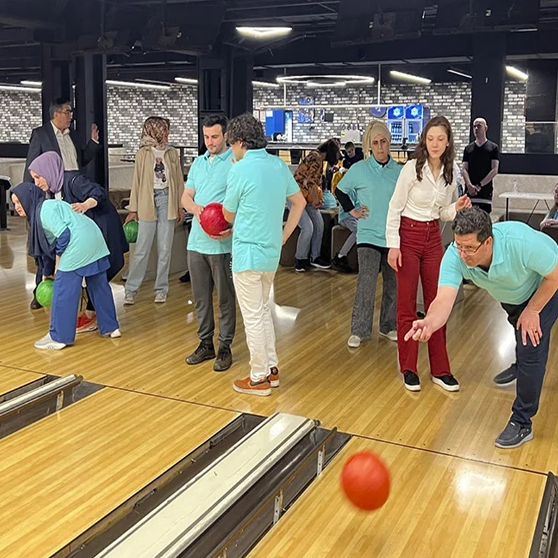 Fotoğrafta bowling oynayan görme engelli bireyler ve eğitimcileri yer alıyor.
